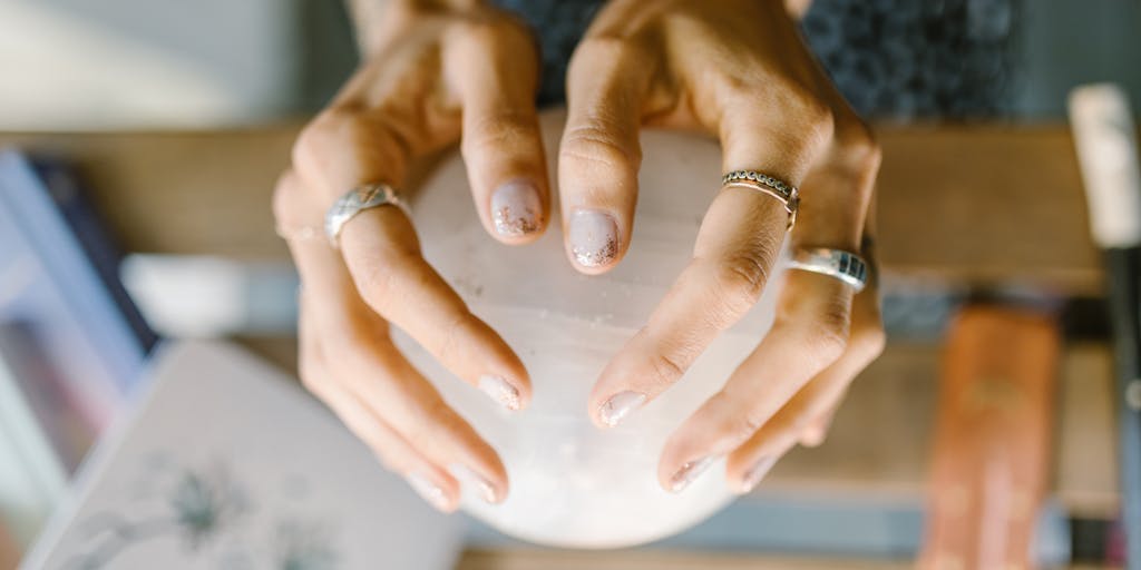 A close-up shot of two hands holding different objects. One hand holds a perfectly formed, smooth, and polished crystal ball, representing the 'theoretical' – a clear, predictable outcome. The other hand holds a handful of rough, jagged, and varied stones, representing the 'hypothetical' – a collection of possibilities with uncertain results. The background should be blurred and neutral, focusing attention on the hands and objects.