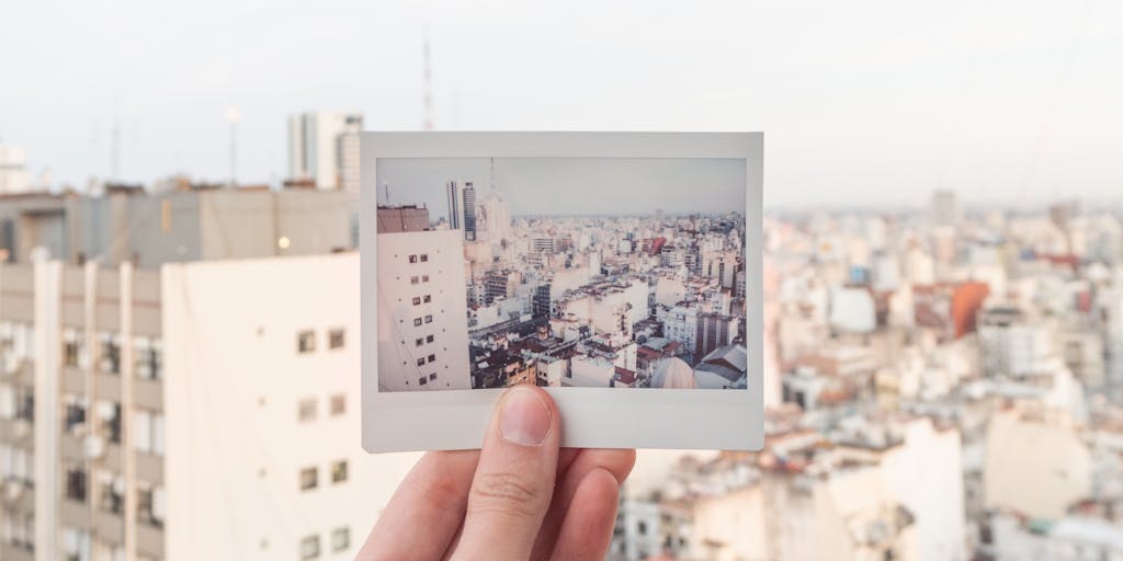 A close-up shot of a hand signing a document, with the focus on the pen and the signature area. The background is slightly blurred, showing a glimpse of a city skyline through a window, subtly hinting at the 'city and state' context. The lighting should be natural and slightly warm, emphasizing the importance of the act of signing.