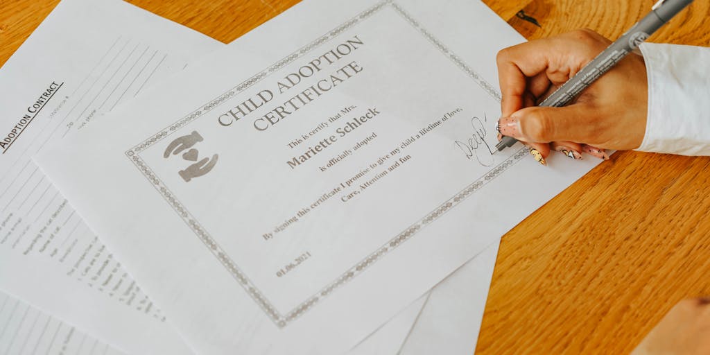 A close-up shot of a legal document, specifically a restraining order or custody agreement, with a child's small hand gently resting on the edge of the paper. The focus is on the document, but the child's hand subtly conveys the emotional weight and protection the legal action provides. The lighting should be soft and slightly dramatic, emphasizing the importance of the document.