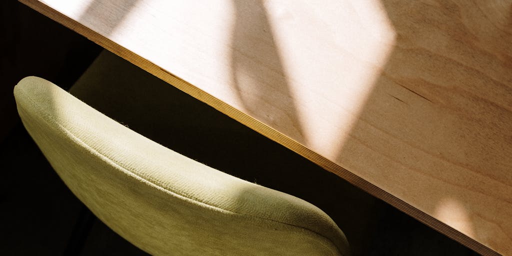 An overhead view of a home workspace with a laptop, legal books, and a notepad filled with notes. The scene includes a window with natural light streaming in, and a family member or pet in the background, illustrating the balance of work and home life for lawyers working remotely.