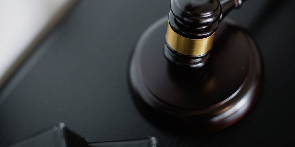 A lawyer participating in a virtual court hearing via video call, with a professional background set up at home. The image captures the lawyer in a suit, looking focused on the screen, while the home environment is subtly visible, showcasing the reality of remote legal work.