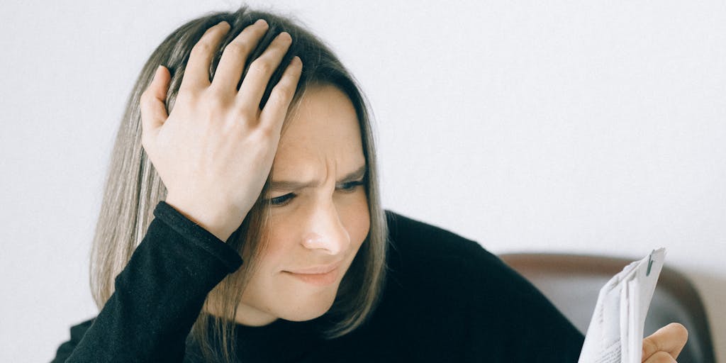 A conceptual photo of a person sitting at a desk, surrounded by paperwork and a calculator, looking stressed while calculating their pain and suffering compensation. The background features a blurred image of a family photo, representing the emotional toll of the injury.