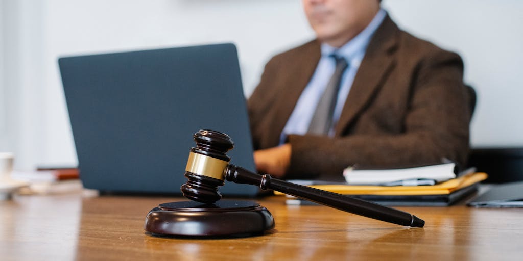 A close-up shot of an attorney's hands typing on a laptop, with a visible error message on the screen indicating a non-mobile friendly site. The focus is on the hands and the screen, capturing the frustration and urgency of the situation, while the background subtly includes legal books and documents.