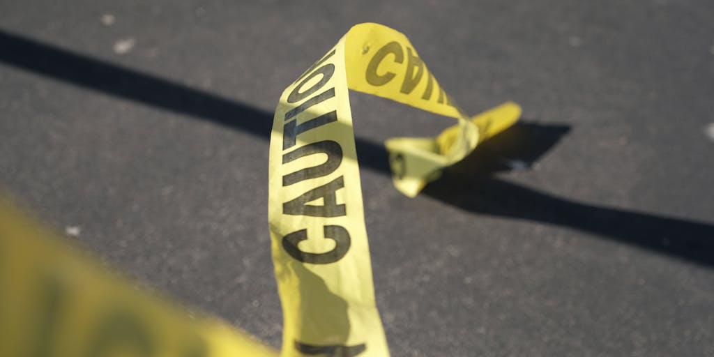 A dramatic shot of a construction site with caution tape in the foreground, and a silhouette of a worker being assisted by a colleague in the background. The scene conveys urgency and the need for legal awareness after an injury.