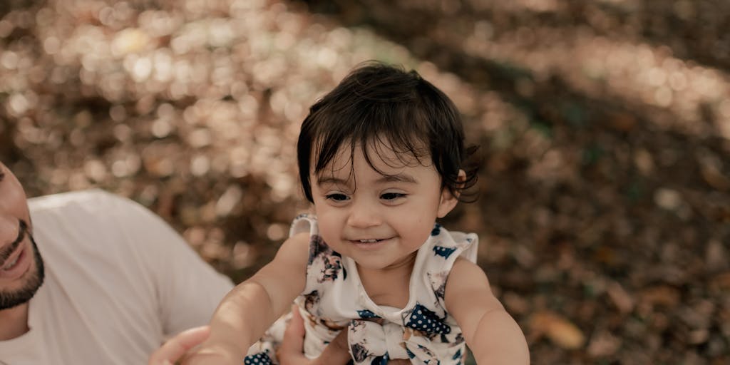 A split image showing two contrasting scenes: on one side, a parent joyfully playing with their child in a park, and on the other side, a stack of bills and a calculator on a table, symbolizing the financial burden of child support. The juxtaposition highlights the emotional and financial aspects of parenting.