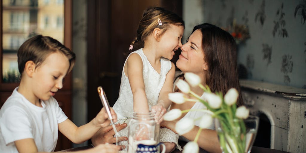 A candid moment of a parent discussing finances with a child at a kitchen table, with papers and a laptop open in front of them. The image conveys the importance of communication about money matters in a family, especially regarding child support and financial planning.