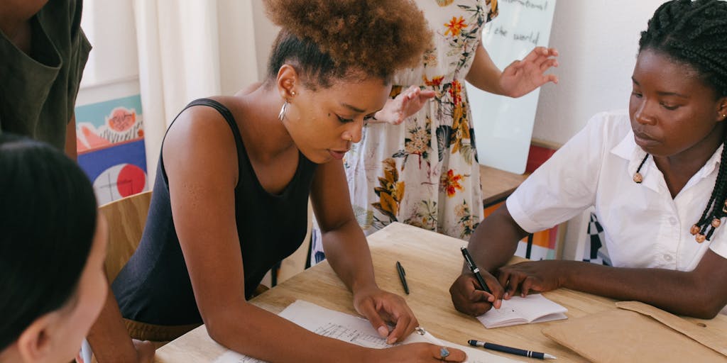 An image of a diverse group of people sitting around a table in a modern office, engaged in a discussion. One person is pointing at a document, while others are taking notes. This represents collaboration and the importance of asking the right questions when selecting a trust and estate lawyer.