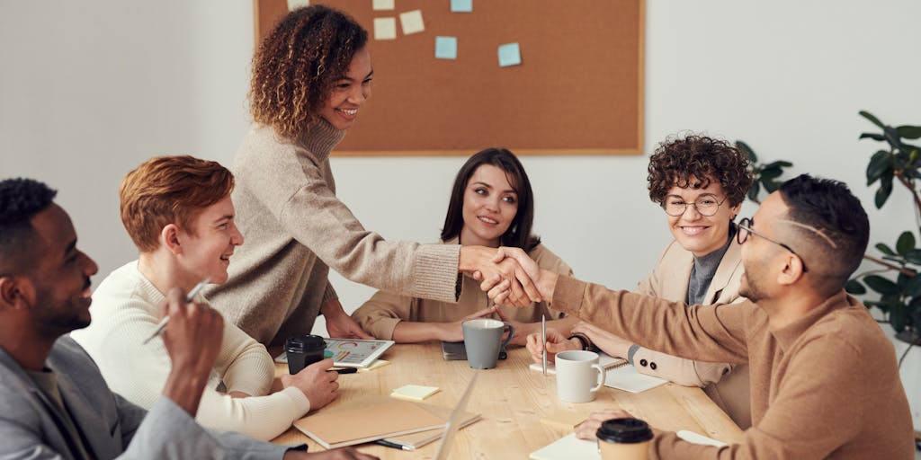 A cozy office space with a small team gathered around a laptop, enthusiastically discussing their Google Workspace setup. The scene captures a mix of excitement and collaboration, with colorful sticky notes and coffee cups scattered around, symbolizing a creative brainstorming session.