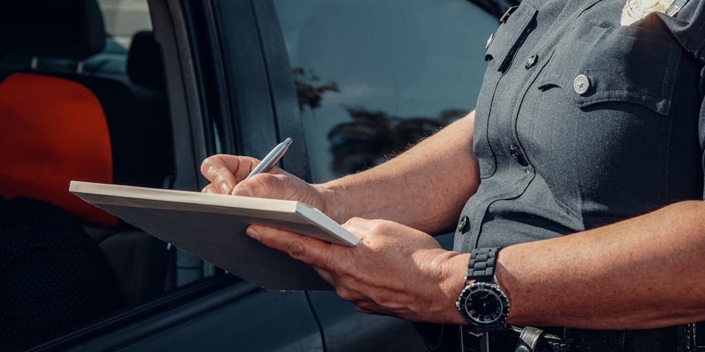 A close-up shot of a police badge and a legal document with the words 'Warrant Required' prominently displayed. The background is blurred to emphasize the badge and document, symbolizing the legal implications of police questioning.