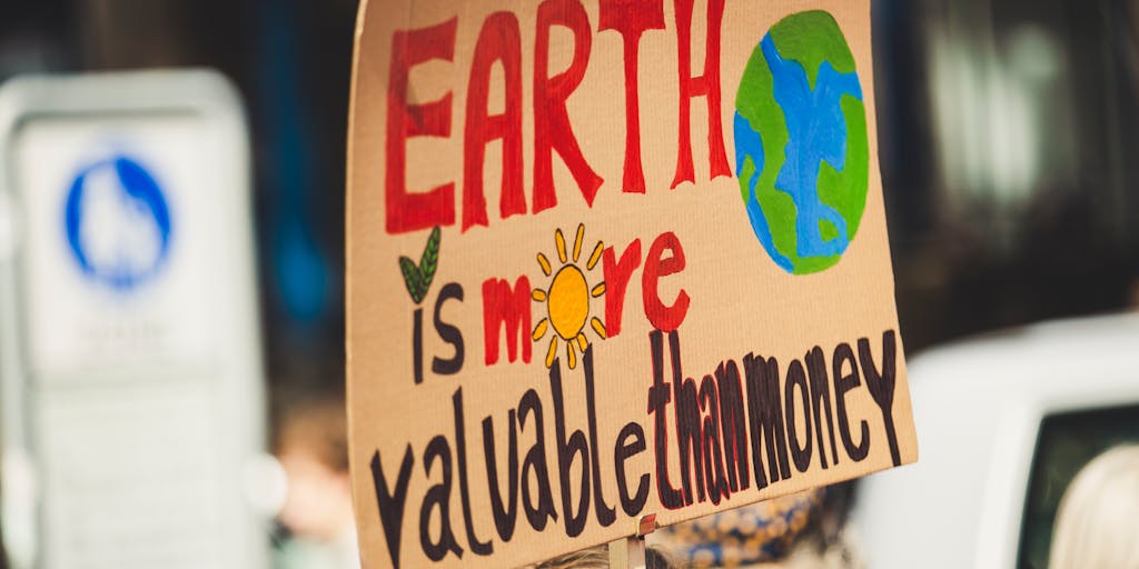 An outdoor scene featuring an environmental lawyer standing in a lush green park, holding a sign advocating for environmental protection. The background shows a city skyline, symbolizing the intersection of law and environmental activism. This photo represents the growing field of environmental law and the lawyer's commitment to sustainability.