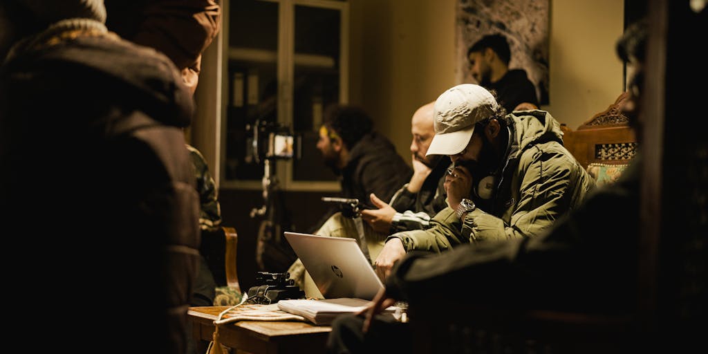 A conceptual image of a group of diverse people sitting around a table, engaged in a discussion with a large sheet of paper labeled 'Bylaws' in the center. The atmosphere is collaborative, with sticky notes and pens scattered around, indicating brainstorming and teamwork.