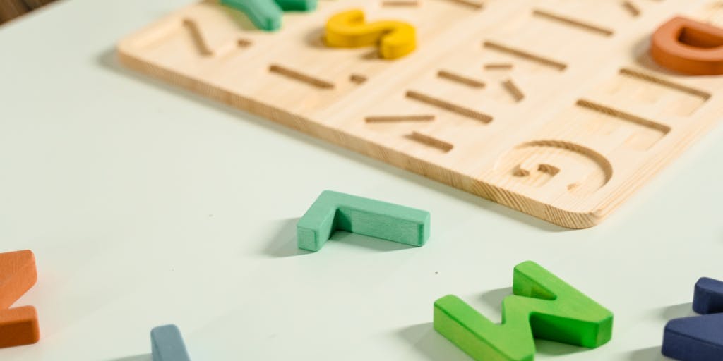 An artistic representation of a C note made from various materials, such as fabric, paper, and metal, arranged in a visually appealing way on a wooden table. The photo captures the textures and colors of each material, highlighting creativity.