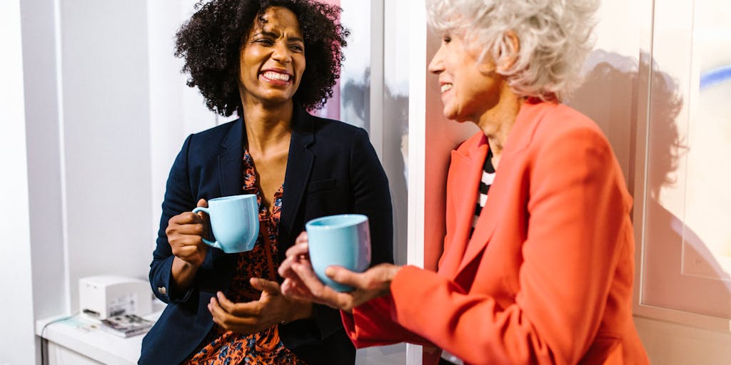 A candid photo of a mentor and a new hire engaged in a discussion over coffee, with a warm and inviting office background. This image symbolizes the support and guidance provided during the probation period, emphasizing the importance of mentorship.