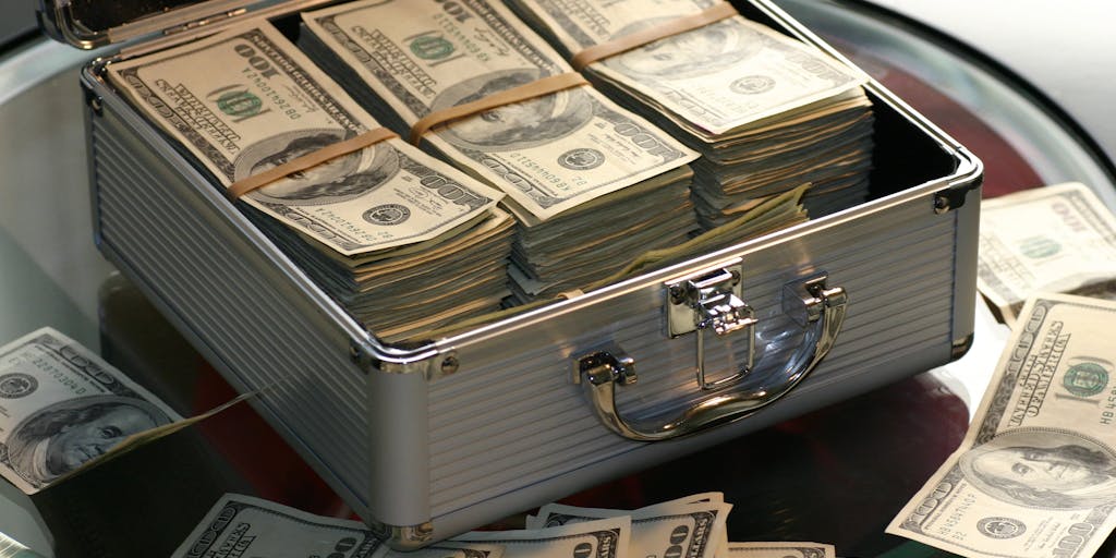 An artistic representation of a lawyer's briefcase overflowing with money, legal documents, and prestigious awards. The briefcase is placed on a polished wooden table, with a Connecticut state flag subtly in the background, symbolizing the financial success of top lawyers in the state.