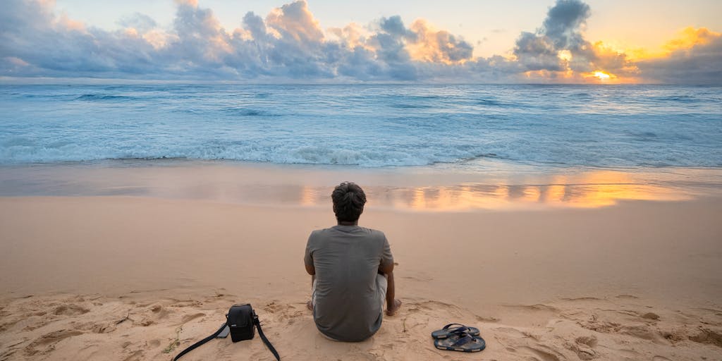 A close-up portrait of a well-dressed lawyer standing confidently on a Hawaiian beach at sunset, with the waves crashing in the background. The lawyer holds a briefcase in one hand and a surfboard in the other, representing the balance between work and leisure in Hawaii's legal profession.