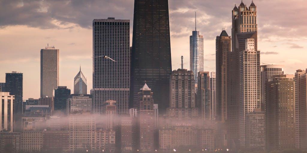 A dramatic overhead shot of a high-rise office building in Chicago, symbolizing the prestigious law firms where the highest paid lawyers work. The image should capture the skyline at sunset, with the building's lights starting to twinkle, conveying a sense of success and ambition.