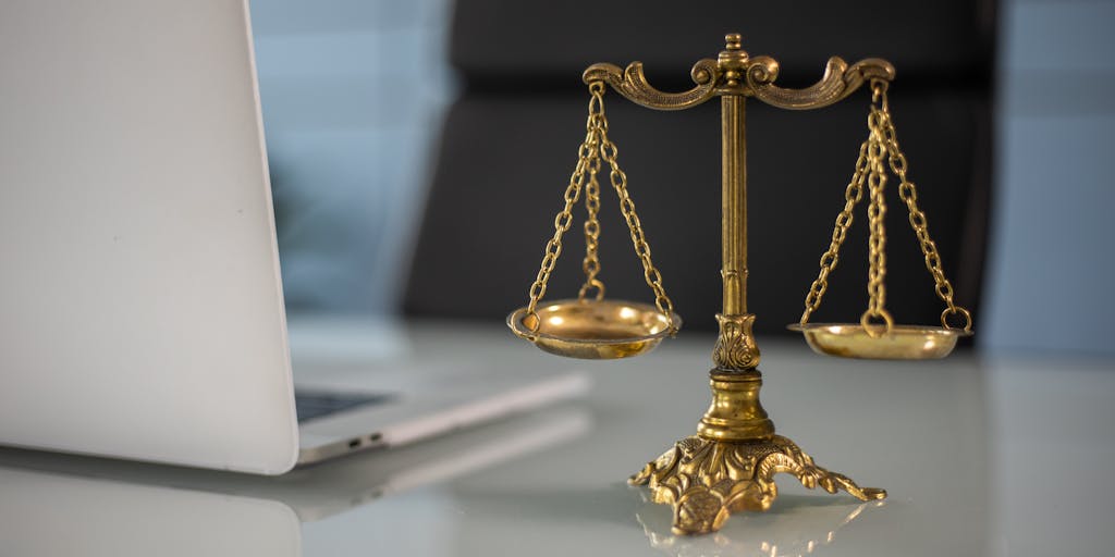 An artistic representation of the scales of justice, made from gold and silver, placed on a marble pedestal. The background features a blurred image of a Kansas courthouse, symbolizing the high value and prestige associated with top legal professionals.