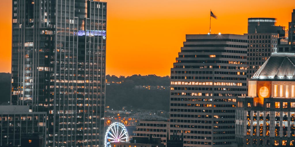 A dramatic overhead shot of a high-rise law office building in downtown Ohio, with the sun setting in the background. The building's name is subtly illuminated, symbolizing the prestige and success of the highest paid lawyers in the state. The image captures the essence of ambition and professionalism in the legal field.