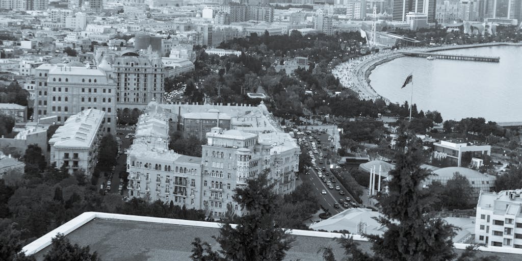 A dramatic shot of a high-rise office building in Baku, symbolizing the power and prestige of the highest paid lawyers in Azerbaijan. The building's glass facade reflects the city skyline, with a focus on the top floors where elite law firms are located. The image captures the essence of success and ambition in the legal profession.