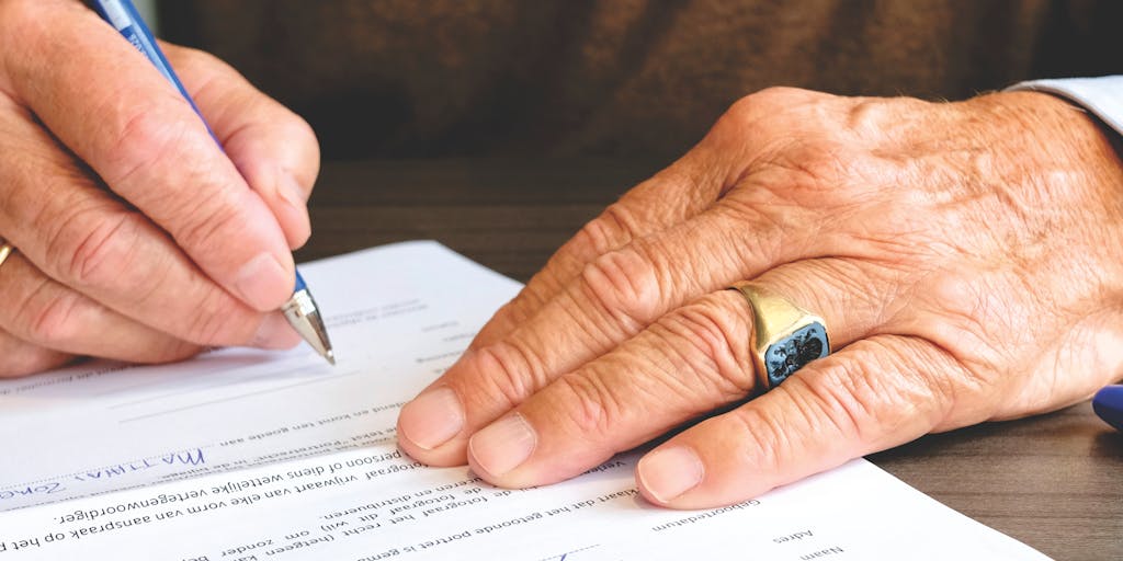 An elegant close-up of a luxury pen resting on a legal document, with a blurred background of a law office filled with books and awards. This symbolizes the meticulous work and high stakes involved in the legal profession.