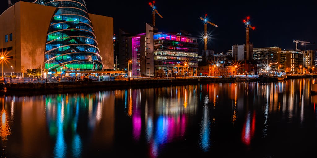 A dramatic shot of a high-rise office building in Dublin, reflecting the skyline at sunset. The building should have a sign indicating it houses a prestigious law firm, symbolizing the success and wealth of the highest paid lawyers in Ireland.