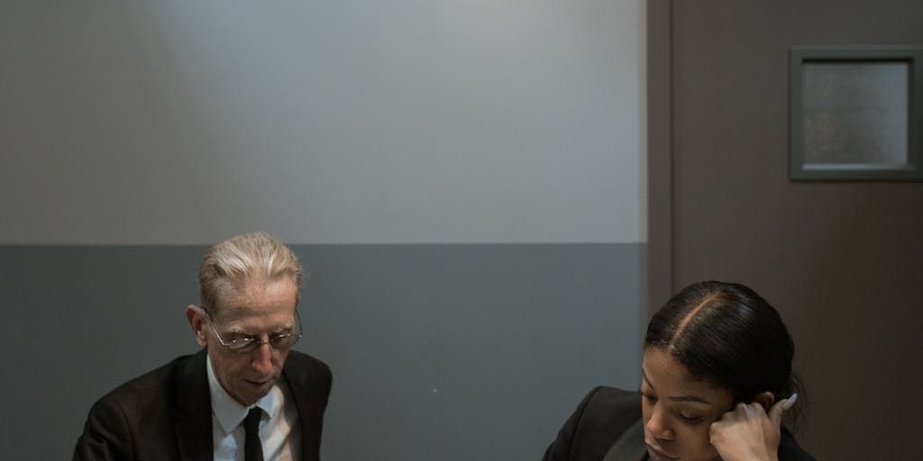 A candid moment of a group of top lawyers in Jamaica engaged in a lively discussion over a case, with a whiteboard filled with legal strategies in the background. This photo showcases collaboration and the dynamic nature of high-stakes legal work.