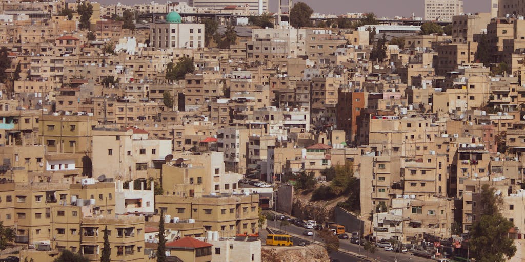 A powerful image of a lawyer standing in front of the Jordanian flag, with a cityscape in the background. The lawyer is looking confidently towards the horizon, symbolizing ambition and the pursuit of justice, representing the highest echelons of the legal profession in Jordan.