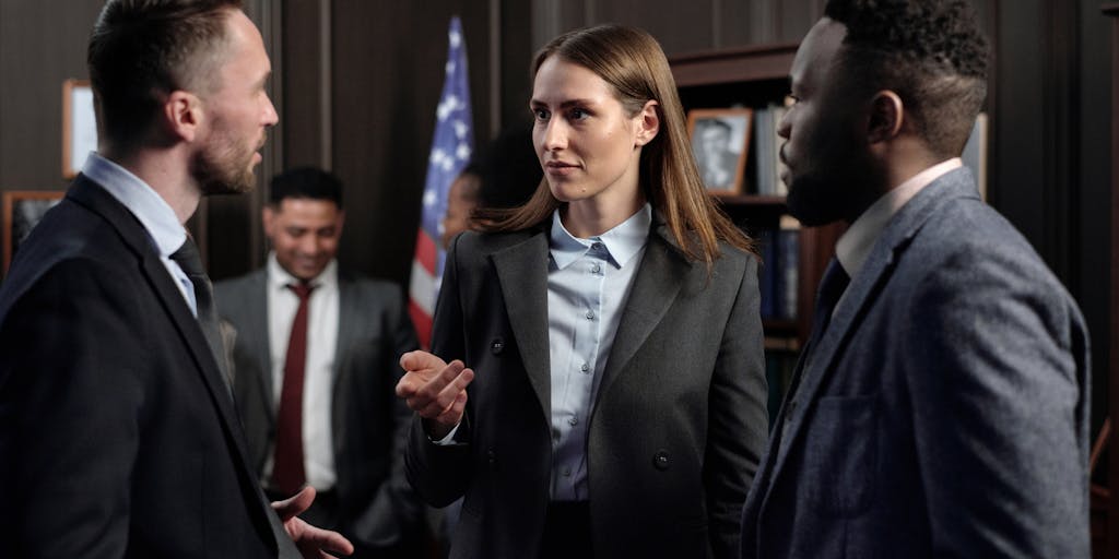 A group of diverse lawyers in a high-end conference room, engaged in a serious discussion over a large table filled with legal books and laptops. The image should convey teamwork and the collaborative nature of high-stakes legal cases, showcasing the elite environment in which these lawyers operate.