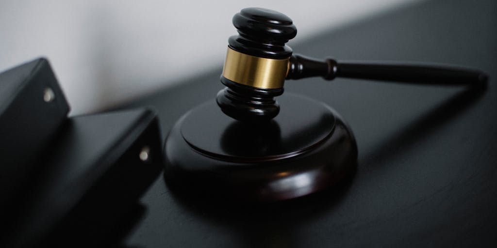 An artistic shot of a gavel striking a sound block, with a blurred background of a courtroom filled with people. The focus on the gavel represents the authority and impact of top lawyers in Kyrgyzstan's legal system.