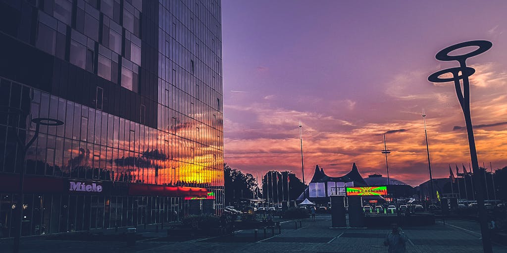 A dramatic shot of a high-rise office building in Bucharest, with a sleek, modern design, symbolizing the success and prestige of the highest-paid lawyers in Romania. The image should capture the building during sunset, with warm light reflecting off the glass facade, creating a sense of ambition and achievement.