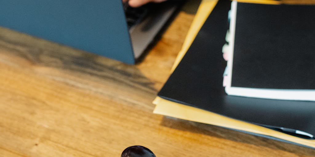 An elegant desk setup featuring a luxurious leather briefcase, a high-end fountain pen, and a stack of legal documents. The background includes a blurred view of a cityscape, representing the bustling legal environment in San Marino. This composition conveys professionalism and success.