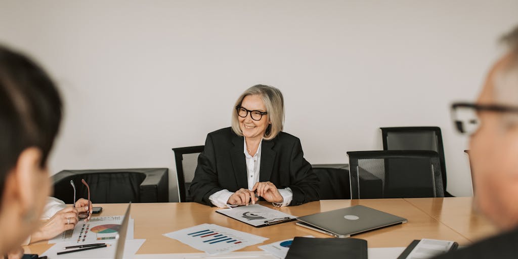 A group of diverse, high-powered lawyers in formal attire engaged in a strategic discussion around a large conference table. The setting should be a sophisticated boardroom with city views, showcasing teamwork and collaboration among the highest paid professionals in the legal field.