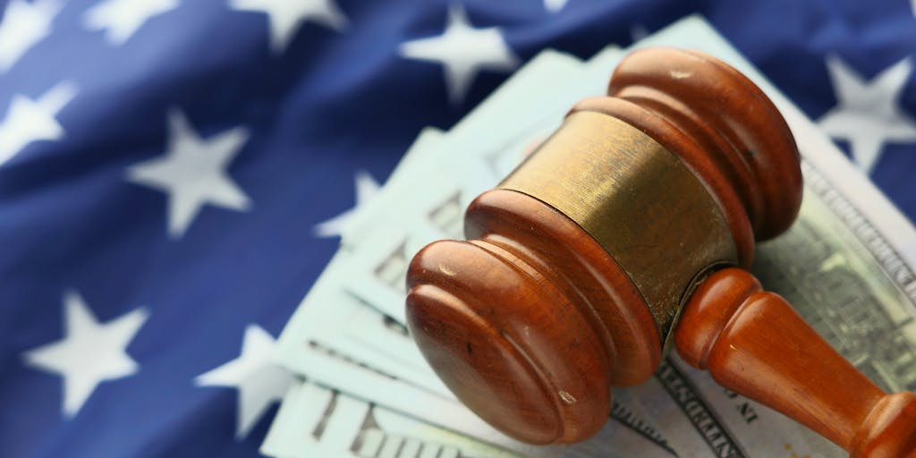 An artistic shot of a gavel resting on a stack of money, with a blurred background of a courtroom. This image symbolizes the intersection of law and wealth, highlighting the financial success of top lawyers in Ukraine.