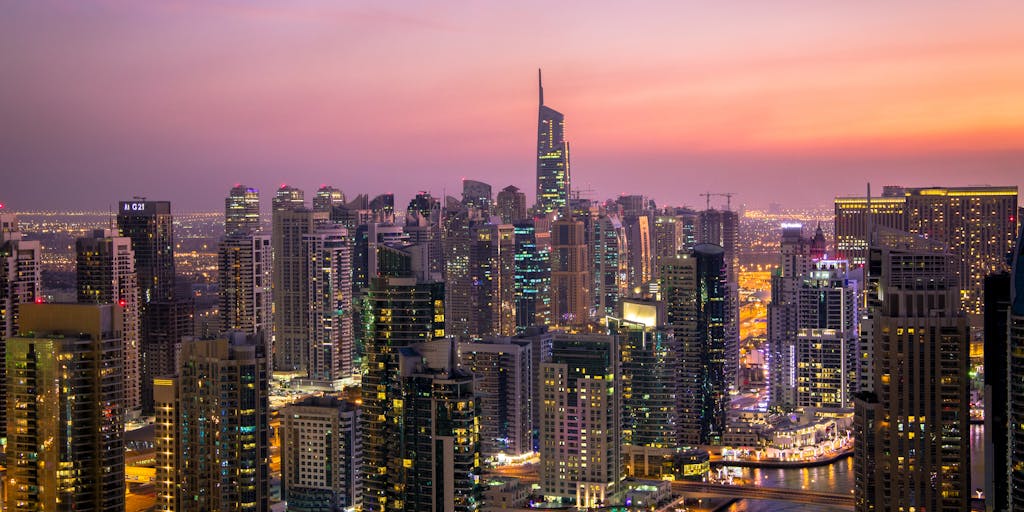 A high-angle shot of a luxurious office space with a panoramic view of the Dubai skyline, featuring a well-dressed lawyer reviewing legal documents. The office is adorned with modern art and high-end furniture, symbolizing success and wealth in the legal profession.