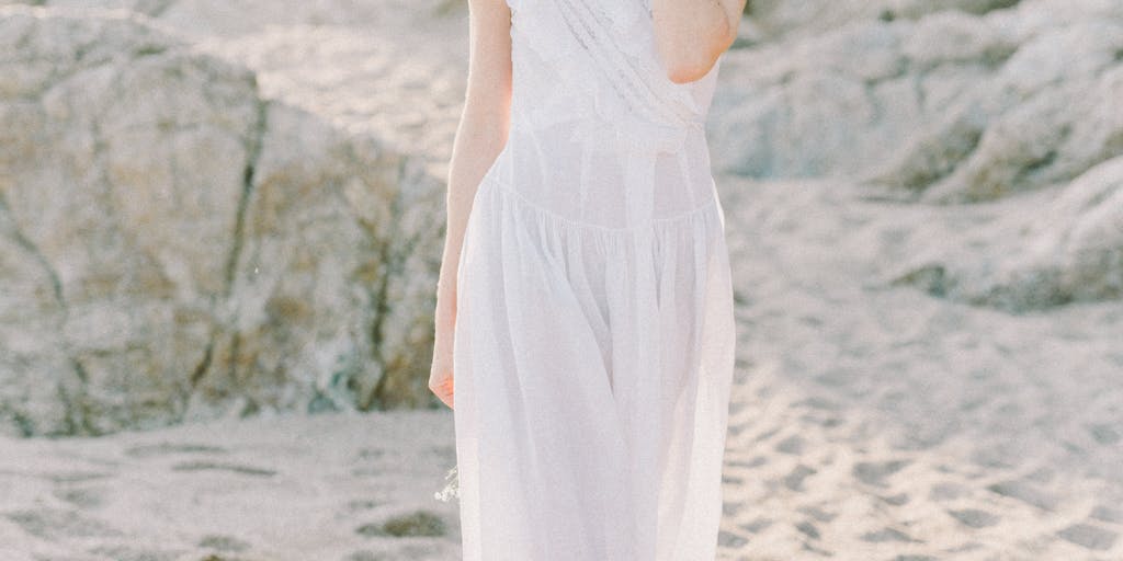 An image of a person standing barefoot on a rocky beach, with waves crashing around their feet. The focus is on their expression of calmness and strength, illustrating the concept of inuring oneself to the cold and discomfort of the ocean.