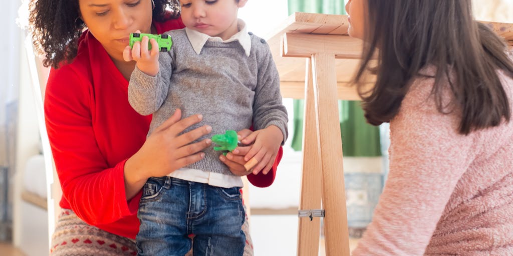 A close-up shot of a hand holding a calculator with child support payment figures displayed on the screen, surrounded by toys and children's drawings. This image symbolizes the financial calculations and considerations that come with child support.