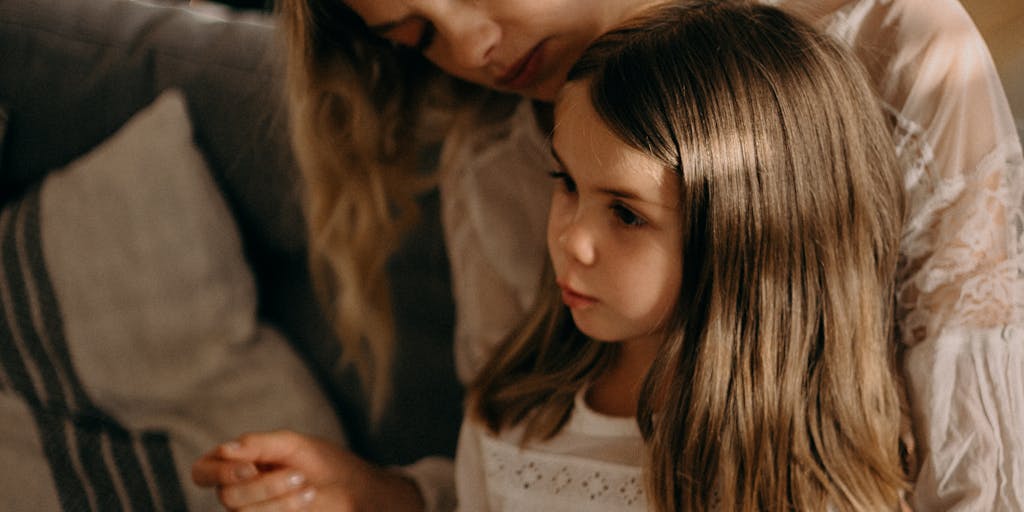 A close-up shot of a hand holding a tax form with a child's drawing in the background. The drawing represents the child's perspective on family, symbolizing the connection between financial responsibilities and emotional ties.