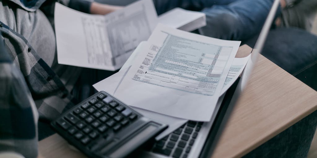 A split image showing a worried parent looking at a pile of bills on one side and a tax form on the other. The bills are labeled with various amounts of child support owed, while the tax form has a big red 'DUE' stamp on it. The contrasting emotions of stress and confusion are captured in the parent's expression.