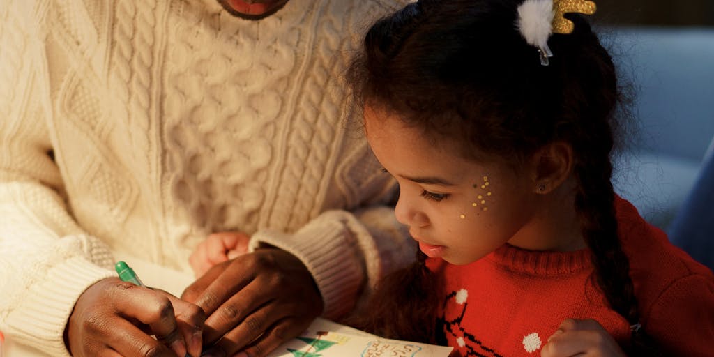 A close-up shot of a hand writing a check for child support, with a child's drawing in the background. This image captures the emotional aspect of financial support and the connection to the child's well-being.