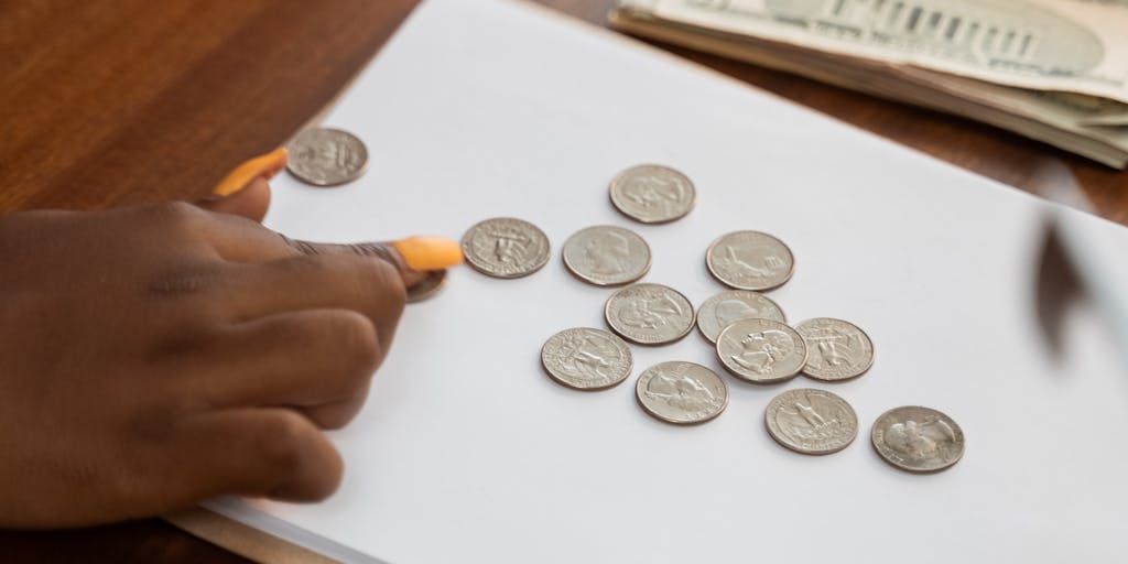 A close-up of a hand writing on a notepad with a list of expenses related to raising a child, such as education, healthcare, and extracurricular activities, with a calculator and a coffee cup in the background, symbolizing the thought process behind calculating child support.