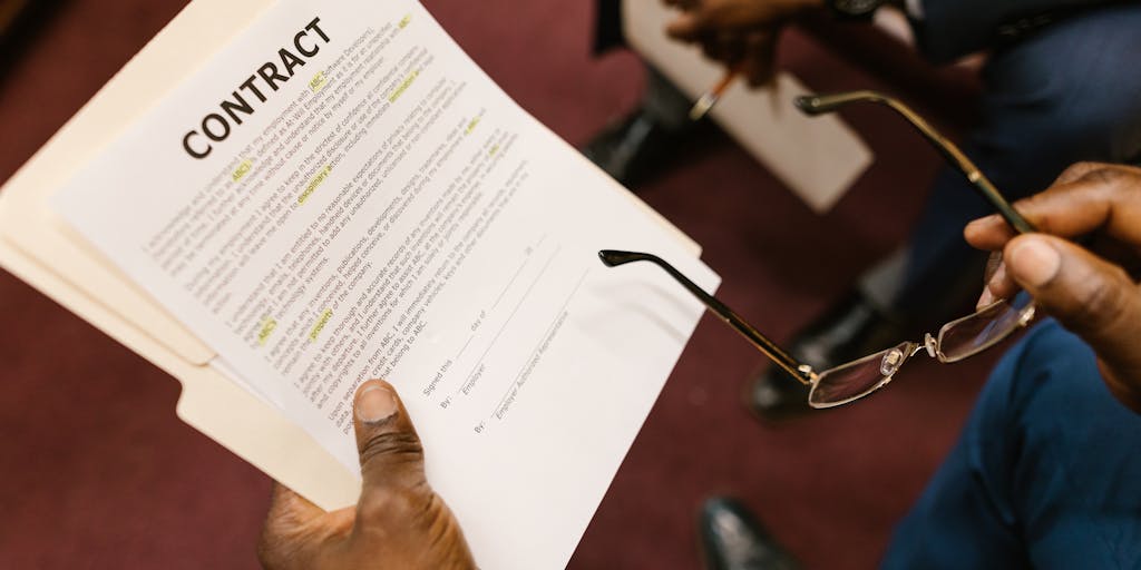 A close-up shot of a pair of hands, one holding a child's drawing and the other holding a legal document. The drawing represents the child's perspective on family, while the legal document symbolizes the complexities of child support. The background is softly blurred to emphasize the hands and the items they hold.