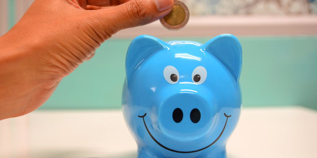 A close-up shot of a broken piggy bank with coins scattered around, symbolizing financial struggles. In the background, a blurred image of a court building can be seen, representing the legal implications of not paying child support.