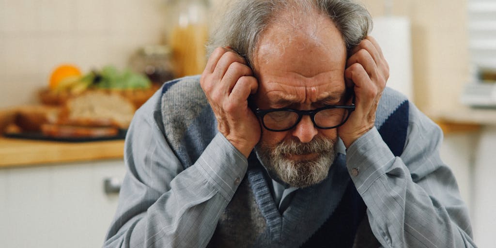 A conceptual image of a person sitting at a kitchen table with bills scattered around, looking contemplative. A calendar on the wall shows a marked date for a child support hearing, emphasizing the stress of financial obligations without income.