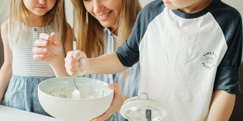 A close-up shot of a parent and child sitting at a kitchen table, with a calculator, bills, and a piggy bank in front of them. The parent is explaining the importance of budgeting for their children's needs, capturing a moment of financial education.