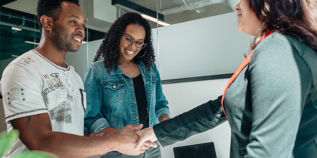 A candid photo of a family meeting with a financial advisor, discussing child support calculations. The advisor is pointing at a chart on a laptop, while the parents look engaged and concerned, illustrating the collaborative effort in determining support.