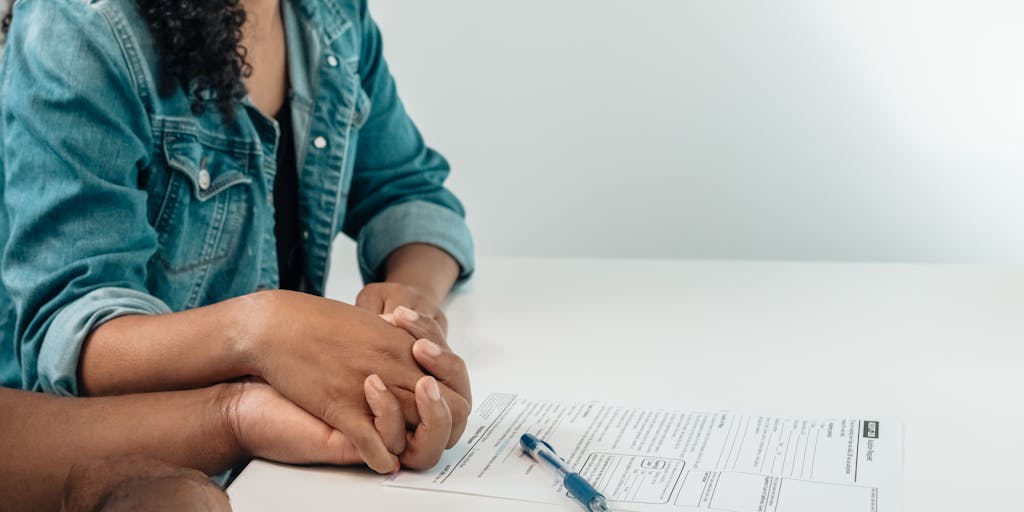 A close-up shot of a pair of hands, one adult and one child, holding a piece of paper that reads 'Child Support Agreement' with a pair of scissors nearby, symbolizing the end of the agreement and the beginning of a new chapter.