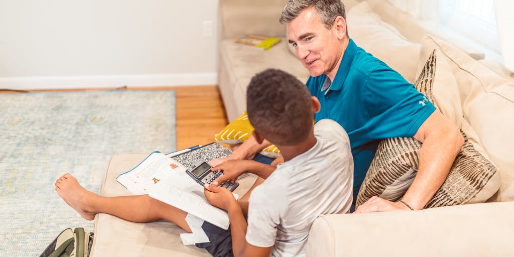 A thoughtful parent sitting at a kitchen table with papers and a laptop, looking contemplative while calculating child support payments. The scene captures the emotional weight and responsibility of financial planning for children.