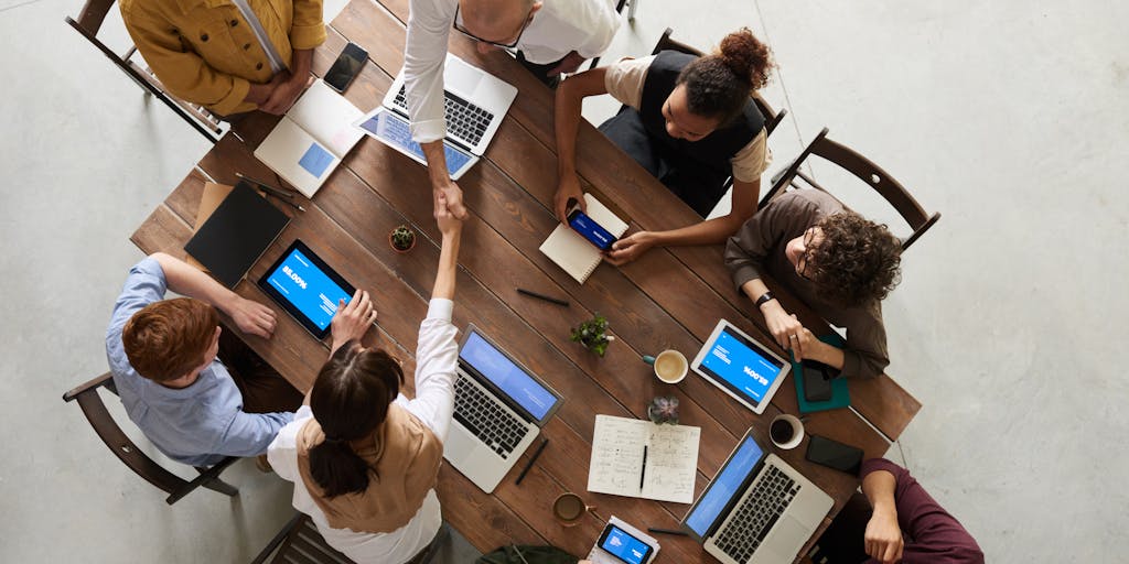 A dynamic image of a diverse group of professionals in a meeting, discussing strategies while looking at a screen that displays Rocketreach analytics. The focus should be on collaboration and the use of technology in business.