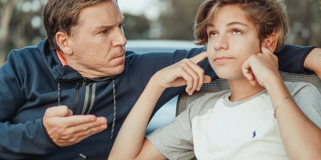 A candid moment of a parent and child sitting together at a kitchen table, reviewing a colorful chart that outlines monthly expenses and child support payments. The image captures the collaborative effort of planning and discussing finances in a supportive environment.