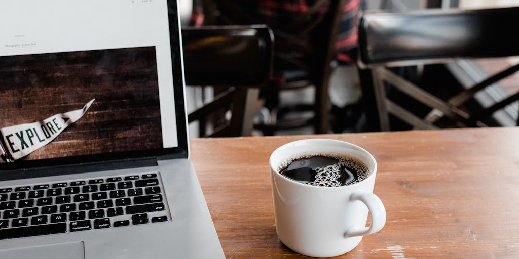 An overhead view of a desk with a laptop open to the Salesloft pricing page, alongside a cup of coffee and a notepad filled with handwritten notes and pricing strategies. The scene is well-lit to create an inviting workspace vibe.